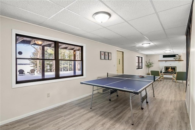 game room with a large fireplace, baseboards, and wood finished floors