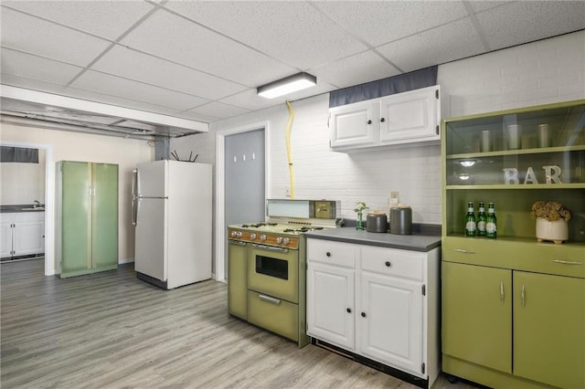 kitchen with dark countertops, stove, freestanding refrigerator, white cabinetry, and light wood-type flooring