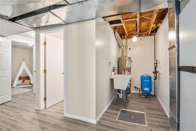 unfinished below grade area featuring gas water heater, baseboards, and wood finished floors