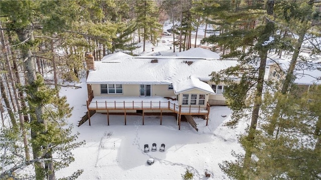 snow covered house featuring a deck and a chimney