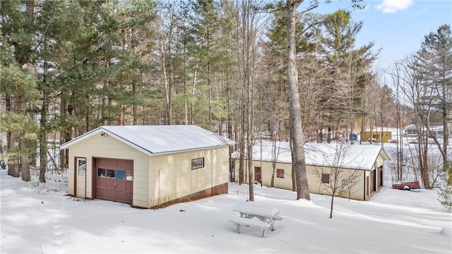snow covered garage with a detached garage