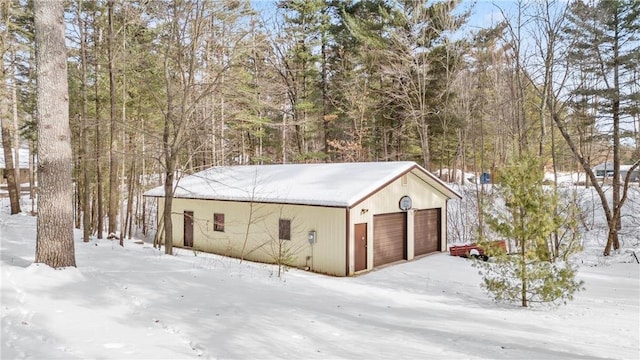 snow covered garage featuring a detached garage