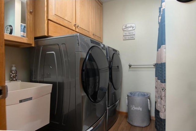 laundry area featuring cabinet space, wood finished floors, separate washer and dryer, and a sink