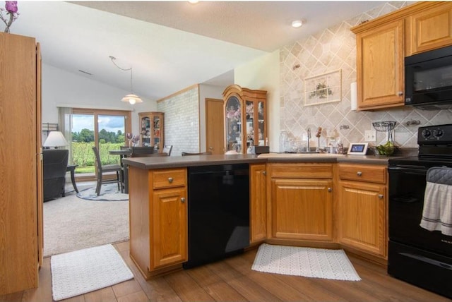 kitchen with brown cabinets, vaulted ceiling, dark countertops, black appliances, and a peninsula