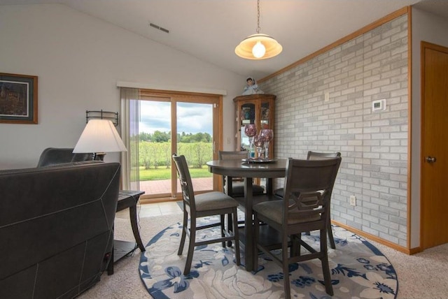 dining space featuring brick wall, light carpet, baseboards, visible vents, and lofted ceiling