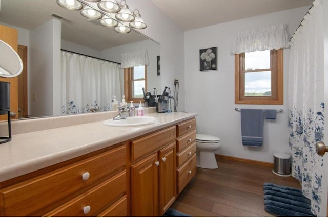 bathroom featuring visible vents, baseboards, toilet, vanity, and wood finished floors