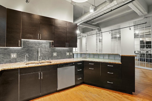 kitchen featuring light stone countertops, a sink, dark brown cabinetry, light wood-type flooring, and dishwasher