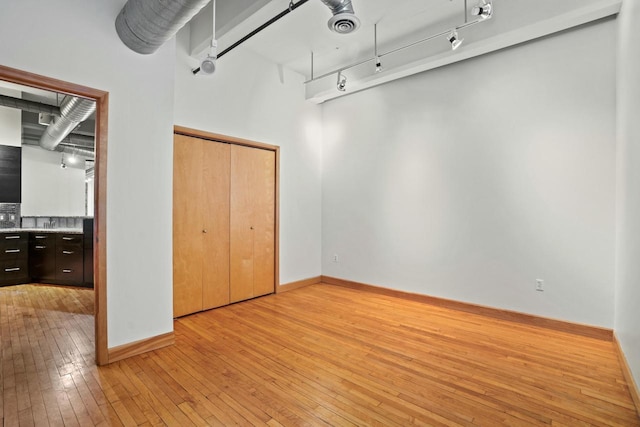 unfurnished bedroom featuring light wood-style flooring, visible vents, baseboards, track lighting, and a closet