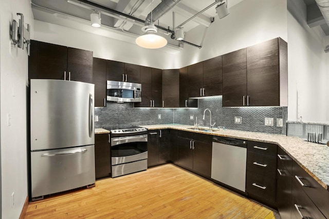 kitchen with stainless steel appliances, a towering ceiling, dark brown cabinets, and a sink