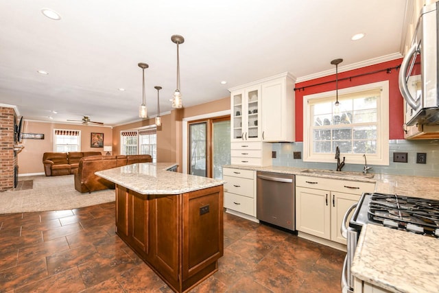 kitchen with hanging light fixtures, stainless steel appliances, open floor plan, a sink, and glass insert cabinets