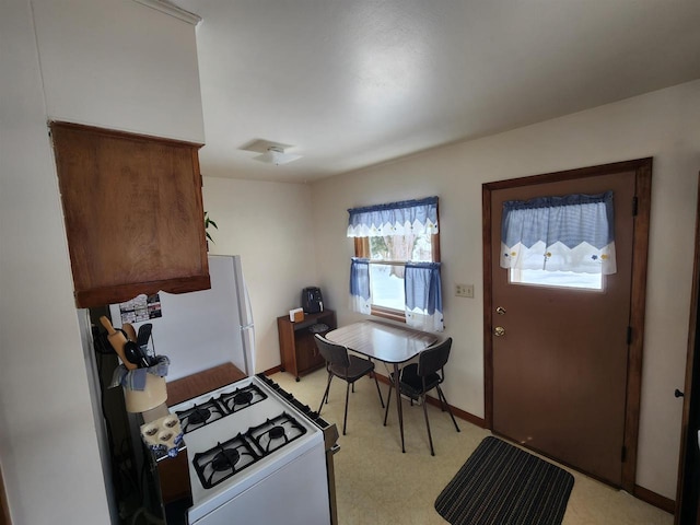 kitchen featuring baseboards and white appliances