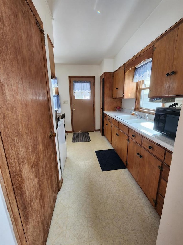 kitchen with a sink, light floors, light countertops, and a wealth of natural light