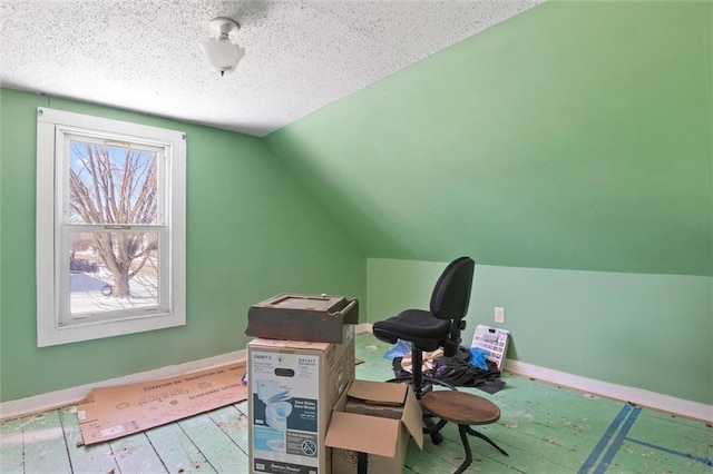 home office featuring vaulted ceiling, light wood-type flooring, baseboards, and a textured ceiling