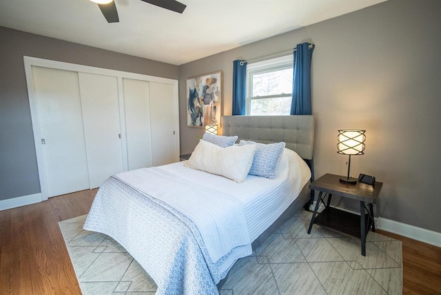 bedroom featuring a ceiling fan, light wood-style floors, baseboards, and two closets