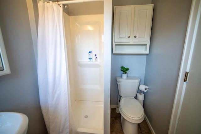 bathroom with baseboards, toilet, and a shower stall