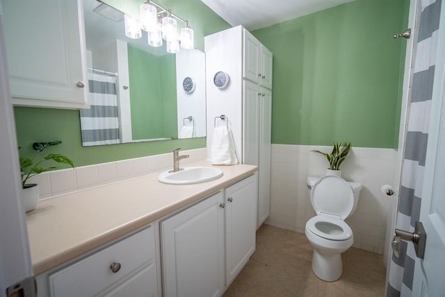 bathroom with toilet, tile walls, wainscoting, tile patterned flooring, and vanity