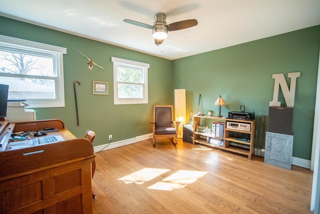 office featuring a baseboard heating unit, baseboards, wood finished floors, and a ceiling fan