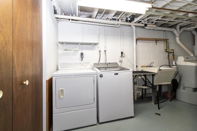 laundry area with concrete block wall, laundry area, a sink, and separate washer and dryer