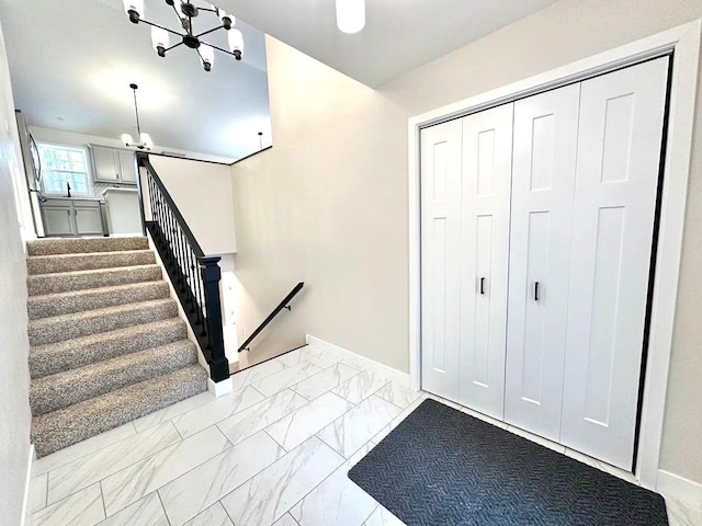 entryway with baseboards, marble finish floor, stairs, and an inviting chandelier