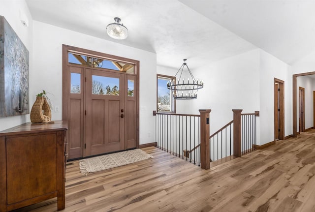 entryway featuring baseboards, light wood-style flooring, and a notable chandelier