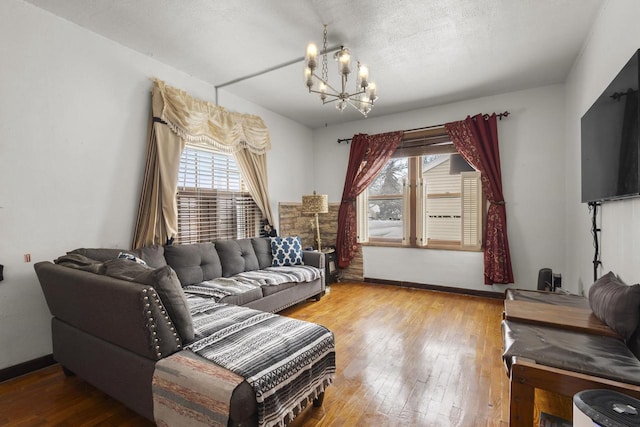 living room with a textured ceiling, an inviting chandelier, wood finished floors, and baseboards