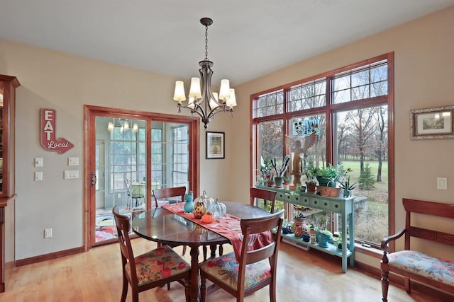 dining space featuring light wood-style flooring, baseboards, and a chandelier