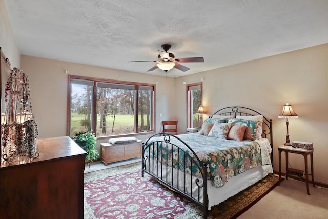 bedroom with light colored carpet, ceiling fan, baseboards, and a textured ceiling