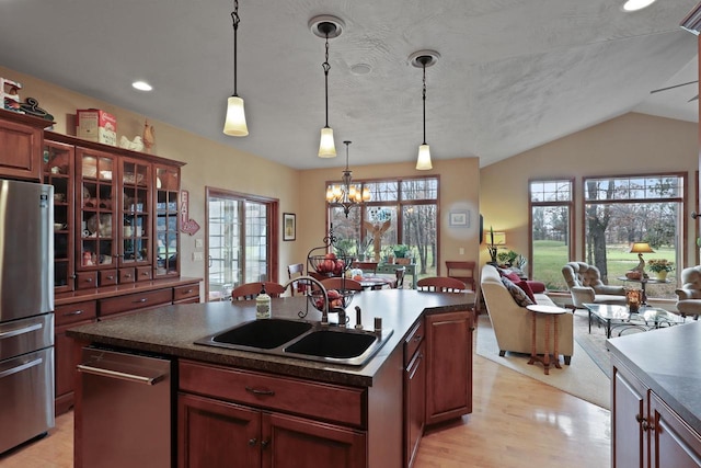 kitchen with dark countertops, freestanding refrigerator, open floor plan, a sink, and glass insert cabinets