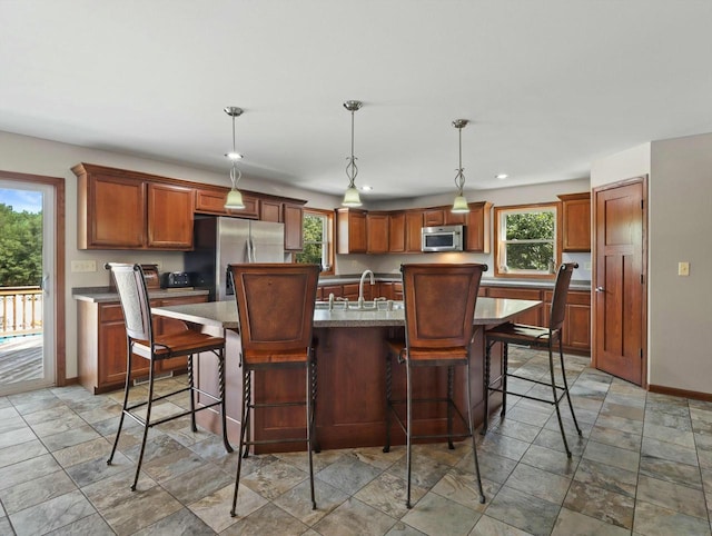 kitchen featuring pendant lighting, a breakfast bar area, stainless steel appliances, a sink, and an island with sink