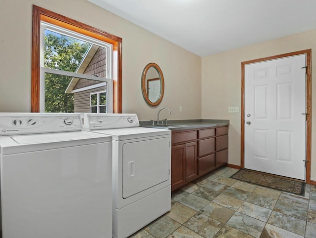 laundry room with cabinet space, baseboards, stone finish floor, washing machine and clothes dryer, and a sink