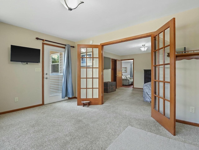 empty room with baseboards, light colored carpet, and french doors