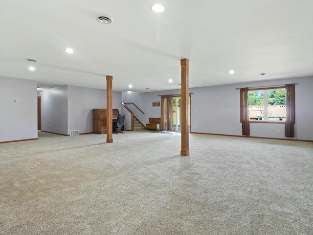 below grade area featuring light colored carpet, visible vents, stairway, and baseboards