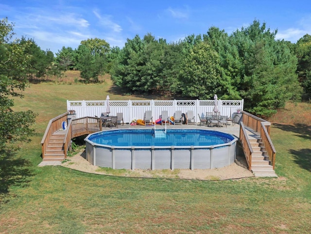 outdoor pool featuring a deck, a yard, stairway, and fence