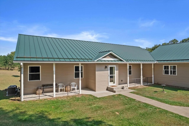 back of property with a standing seam roof, a patio area, a lawn, and central AC unit