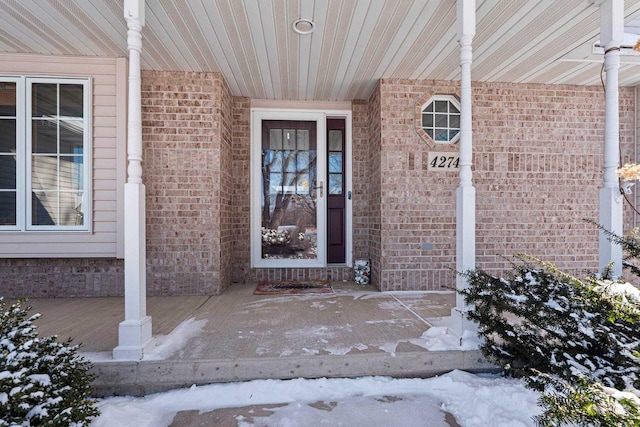 snow covered property entrance with brick siding