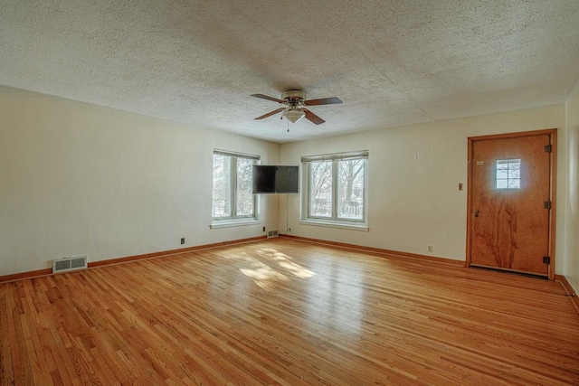 unfurnished living room with ceiling fan, light wood-style flooring, visible vents, and baseboards