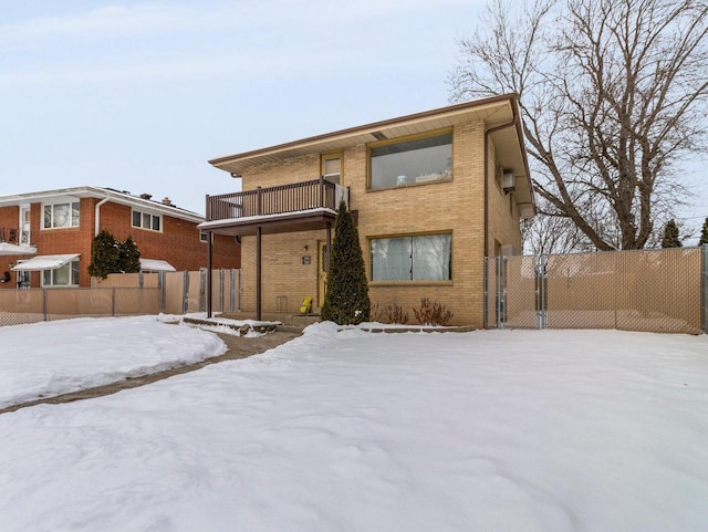 view of front of property featuring a balcony, fence, and brick siding