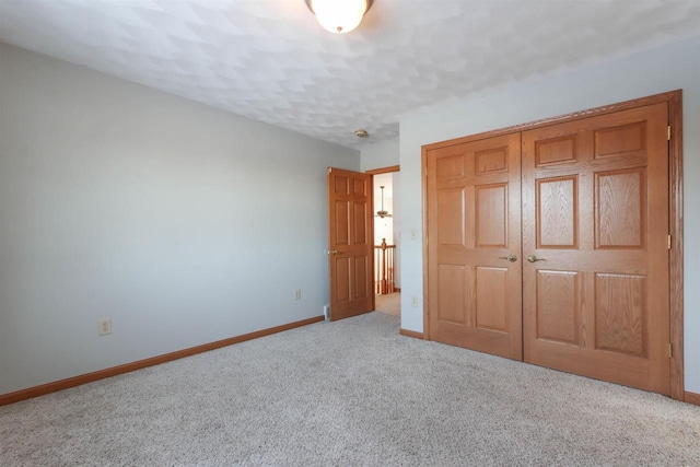 unfurnished bedroom with a closet, light colored carpet, and baseboards