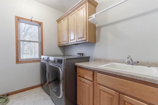 washroom with baseboards, a sink, cabinet space, and washer and dryer