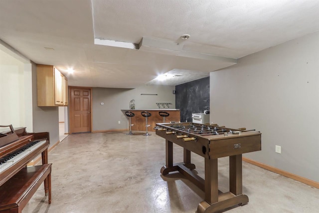 rec room featuring finished concrete flooring and baseboards