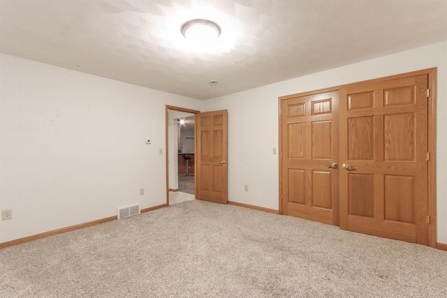 unfurnished bedroom featuring carpet floors, a closet, visible vents, and baseboards