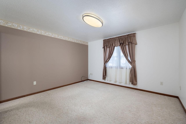 spare room with carpet, baseboards, and a textured ceiling