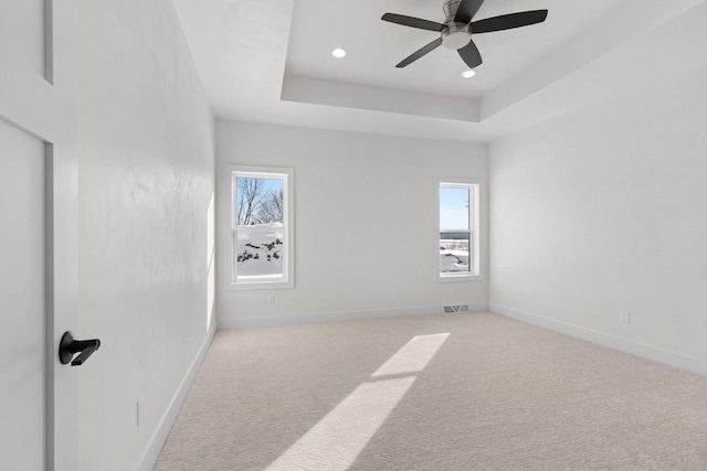 unfurnished room with a healthy amount of sunlight, baseboards, visible vents, and a raised ceiling