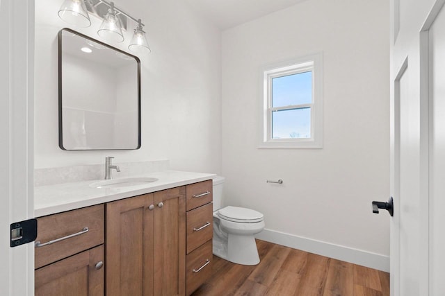 bathroom featuring toilet, baseboards, wood finished floors, and vanity