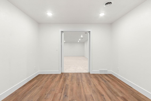 spare room with wood finished floors, visible vents, and baseboards