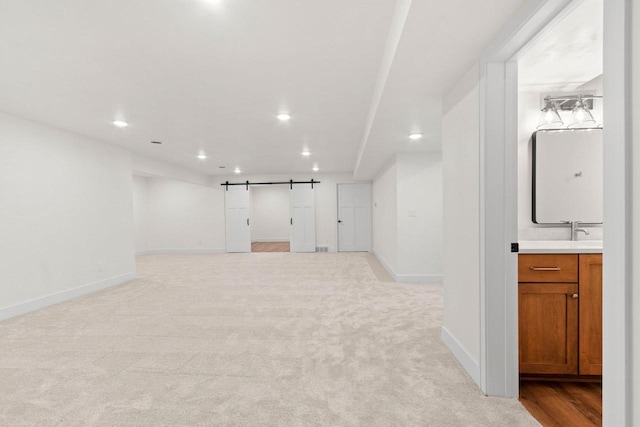 unfurnished room with a barn door, baseboards, light colored carpet, and recessed lighting