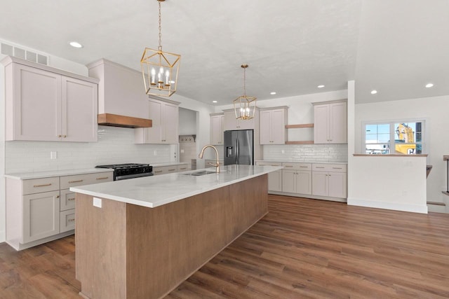 kitchen featuring visible vents, appliances with stainless steel finishes, hanging light fixtures, a large island with sink, and a sink