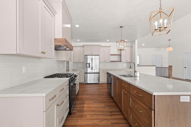 kitchen featuring appliances with stainless steel finishes, decorative light fixtures, custom exhaust hood, white cabinetry, and a sink