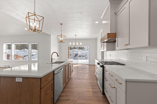 kitchen featuring appliances with stainless steel finishes, white cabinets, a sink, and hanging light fixtures