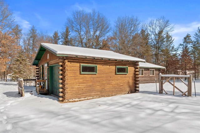 snow covered property featuring a garage and log siding